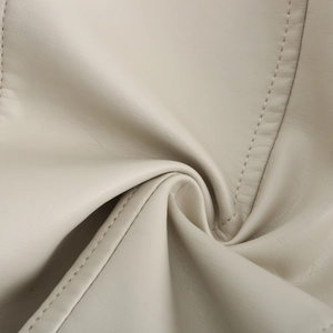 Detailed close-up of cream leather texture with high-quality double stitching and soft folds