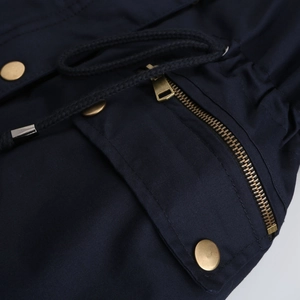 Detailed macro view of navy parka jacket with metal zipper, snaps, and waist drawstring