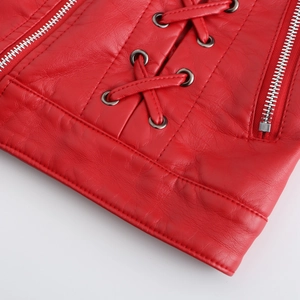 Détail d'une veste en cuir rouge avec laçage croisé, œillets et fermetures argentées