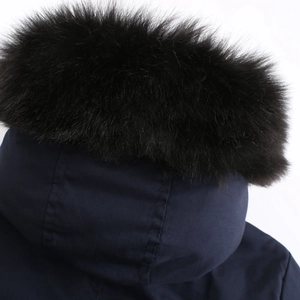 Detail of a dark blue parka featuring a voluminous black faux fur trim on the hood