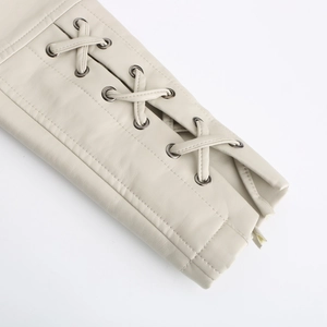 Détail de la veste en similicuir crème avec laçage croisé et œillets métalliques