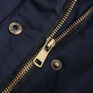 Detail of vintage brass star buttons and metal zipper on navy blue parka jacket