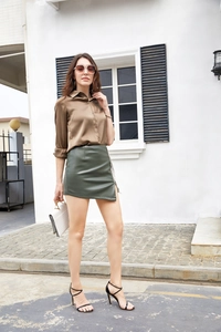 Détail de la fente latérale sur mini-jupe en similicuir avec chaînes à franges en métal