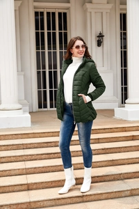 Women's dark green quilted hooded puffer jacket with white knit sweater and jeans