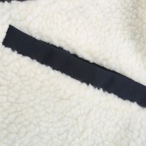 Detail shot of white sherpa fleece texture with deep blue diagonal fabric trim contrast