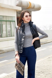 Women's black faux leather vest styled with a grey sweater and leopard print clutch