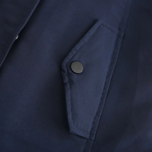 Close-up of navy blue winter parka pocket with matte black metal snap button detail