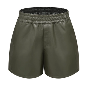 Detail of high-waisted dark green PU leather shorts with elastic waist and center seam