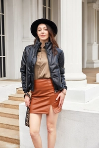 Detail of a women's black PU quilted jacket with a brown mini skirt and a leopard strap bag