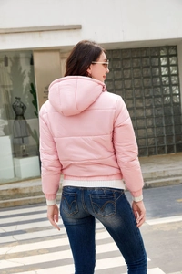 Vista posterior de chaqueta acolchada rosa con capucha para mujer en entorno de calle