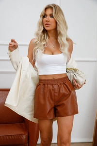 Detail of high-waisted brown faux leather shorts styled with a blazer and handbag