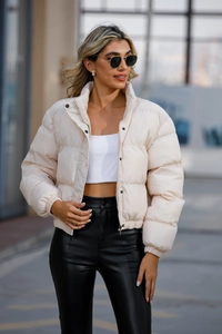 Detailed view of cream-colored short puffer jacket with high collar and quilted texture