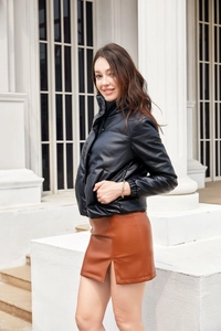 Detail of a black PU leather padded puffer jacket paired with a brown mini skirt