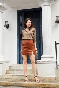 Detail of high waist caramel PU leather mini skirt with a stylish side slit design