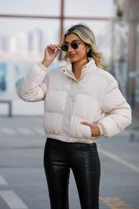 Detail of cream short quilted puffer jacket featuring high collar and button closure