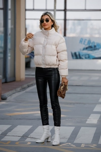 Detailed full-body view of a beige high-collar puffer jacket with black leather trousers