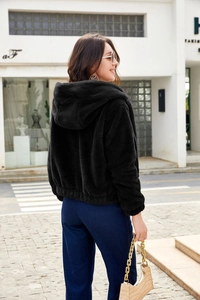 Detail view of the black hooded plush jacket featuring an elastic hem and cozy texture