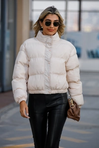 Detail of a beige cropped puffer jacket with high neck collar and button closure