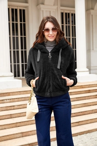 Full body shot of a woman in black plush hooded jacket and dark blue wide-leg trousers