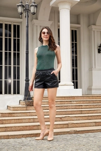 Detail of high-waist black leather shorts paired with a dark green sleeveless knit top