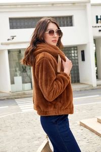Detail of a brown plush hooded jacket with elastic cuffs and cozy faux fur texture