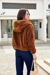 Detail view of the plush texture and back silhouette of a brown faux fur hooded jacket