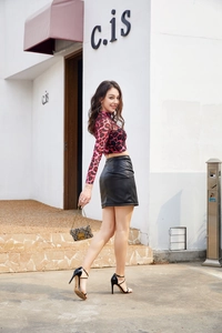 Detail shot of a black high-waisted PU leather mini skirt with a stylish side slit design