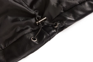 Close-up of drawstring detail with metal toggle and textured leather on black puffer vest