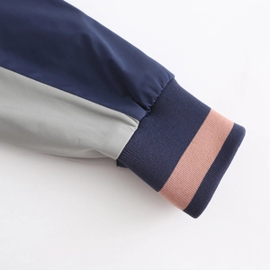 Detail of color-block windbreaker sleeve with navy ribbed cuff and pink stripe accent