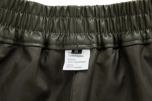 Detail of elastic waistband and material label on green PU leather shorts for women