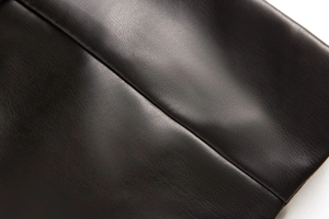 Détail en gros plan de la texture en cuir PU noir avec surpiqûres soignées sur le gilet