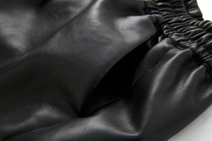 Detail shot of black PU leather shorts with elastic waistband and high-quality stitching