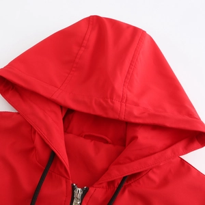 Detail of red windbreaker hood with adjustable black drawstrings and silver zipper