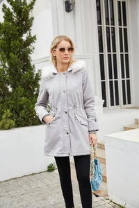Outdoor shot of a women's light grey parka coat with a white faux fur hood and waist drawstring