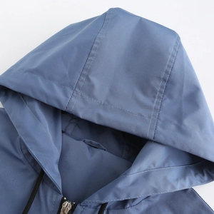 Detailed close-up of hooded windbreaker neckline with zipper and black drawstrings