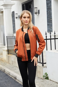 Detail eines burnt orange Bomberjacke-Ärmels mit Utility-Reißverschlusstasche und Rippbündchen