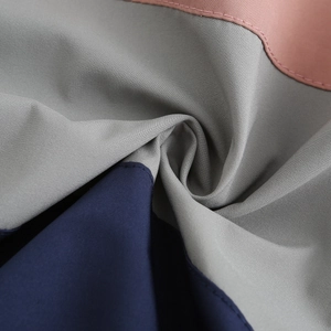 Close-up of tricolor hooded windbreaker fabric showing fine texture and neat stitching