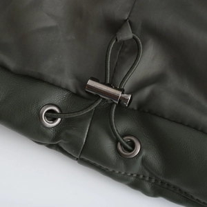 Detail of olive green jacket featuring fabric patchwork and metal drawstring toggles