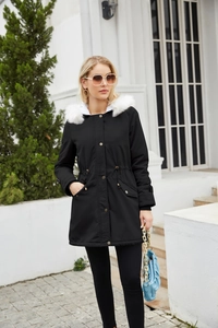 Women's black parka with a large white faux fur hood shown in a full-length street view