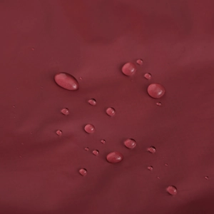 Vue macro montrant la texture déperlante et les gouttes sur le tissu rouge de la veste