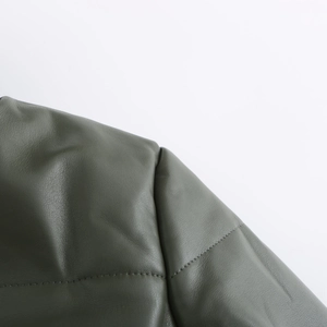 Close-up of olive green faux leather jacket texture and precision stitching details