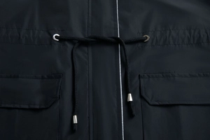 Detail of adjustable waist drawstring and metal eyelets on a black hooded trench coat