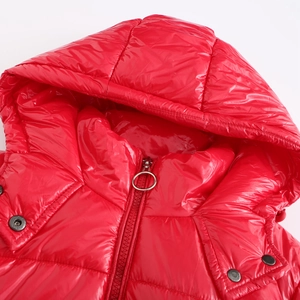 Detalle de chaqueta acolchada roja brillante con capucha, cremallera plateada y broches
