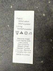 Detail view of cotton coat care label showing fabric composition and washing instructions