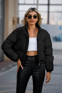 Close-up of black quilted puffer jacket featuring a high collar and snap-button closure
