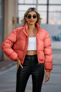 Detail of coral cropped puffer jacket with stand collar and zipper closure in city setting
