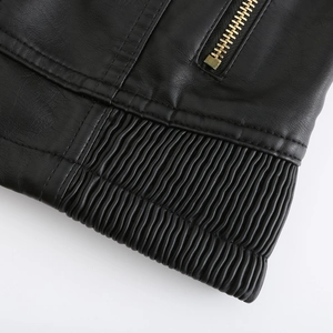 Detailed macro view of the black leather jacket gold zipper and elastic ribbed hem
