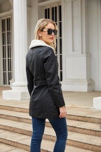 Detail view of the black faux leather jacket featuring a contrast white faux fur collar