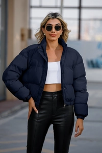 Detailed view of women's navy blue quilted jacket with high stand-up collar and button closure
