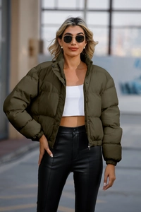 Detail view of olive green quilted puffer jacket featuring high collar and metal snap buttons